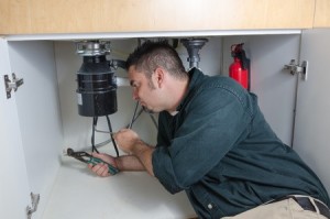 Image of a Man under a Sink Working on a Garbage Disposal